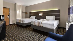 Habitació d'hotel amb dos llits, una taula de treball, una cadira i una catifes amb dibuixos.