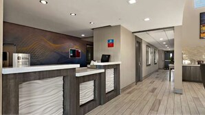 A hotel reception area with a modern design, including a reception desk, a digital screen, and a sign indicating a loyalty program. - Surestay Plus Hotel by Best Western Tulsa East (Tulsa)