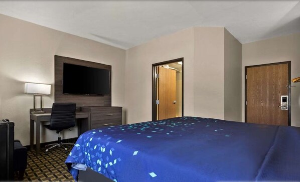 A hotel room with a bed, a desk with a chair, a television, and a door. - Surestay Plus Hotel by Best Western Tulsa East (Tulsa)