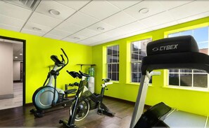 A gym with exercise equipment, bright yellow walls, and large windows. - Surestay Plus Hotel by Best Western Tulsa East (Tulsa)