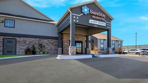 Un hotel SureStay Plus BEST WESTERN amb façana de pedra, un vestíbul cobert i un aparcament.