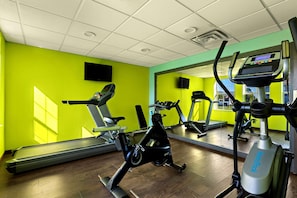 Ein Fitnessstudio mit Trainingsgeräten, Laufband und Spiegelwand.