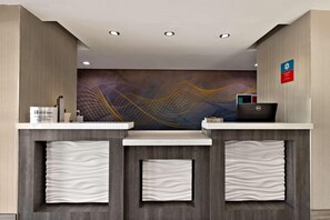 A reception desk with a modern design, a digital screen, and a wall mural. - Surestay Plus Hotel by Best Western Tulsa East (Tulsa)