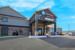 A SureStay Plus Hotel by BEST WESTERN with a stone facade, a covered entrance, and a parking lot. - Surestay Plus Hotel by Best Western Tulsa East (Tulsa)
