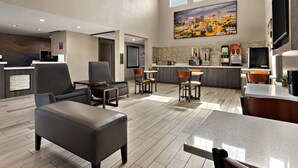 A hotel lobby with a reception desk, seating area, kitchen, and a large painting on the wall. - Surestay Plus Hotel by Best Western Tulsa East (Tulsa)