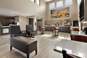 A hotel lobby with a reception desk, seating area, kitchen, and a large painting on the wall. - Surestay Plus Hotel by Best Western Tulsa East (Tulsa)