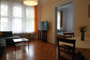 Ein Wohnzimmer mit einer Couch, Couchtisch, Fernseher und einem Essbereich mit Stühlen und Tisch.