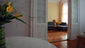 An open door leading to a living room with a sofa, a coffee table, and a vase with flowers. - Gohlis city apartment (Leipzig)