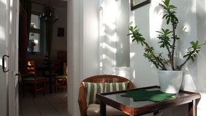A dining area with a wicker chair, a table with a green placemat, and a potted plant. - Gohlis city apartment (Leipzig)