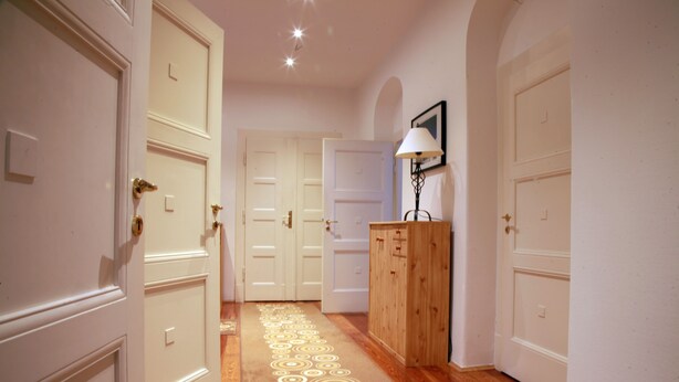 A hallway with wooden flooring, white doors, and a lamp on a wooden cabinet. - Gohlis city apartment (Leipzig)