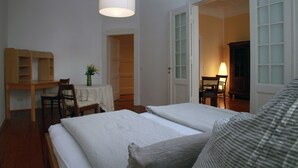 A bedroom with a bed, a desk, and a chair. There is a door leading to another room. - Gohlis city apartment (Leipzig)