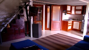 Un espacio habitable pequeño con kitchenette, un sofá azul, una escalera y un televisor.