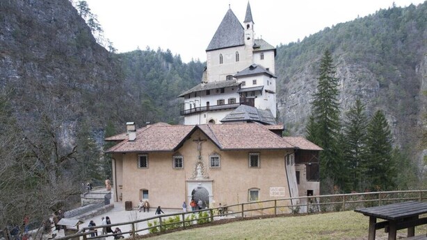 Un edificio histórico con una torre central, un campanario y una estatua al frente.