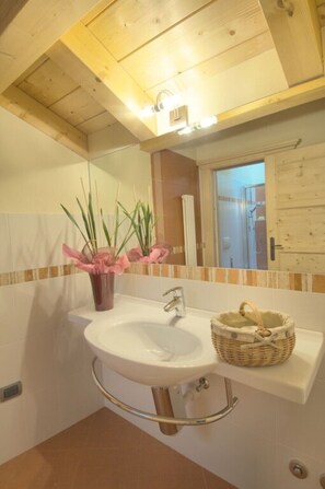 A bathroom with a white sink, a mirror, and a wooden ceiling.