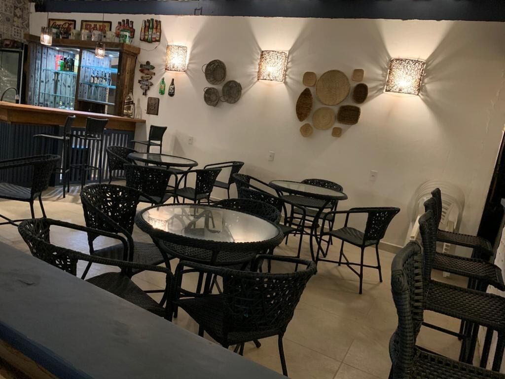 A bar area with a counter and seating. There are tables and chairs arranged around the bar.