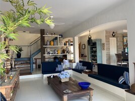 Een ruime woonkamer met een houten salontafel, een blauwe bank en een trap naar een tweede verdieping.
