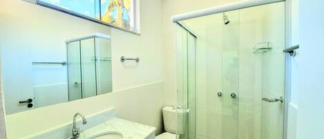 A modern bathroom with a glass shower enclosure, a sink with a mirror, and a toilet.