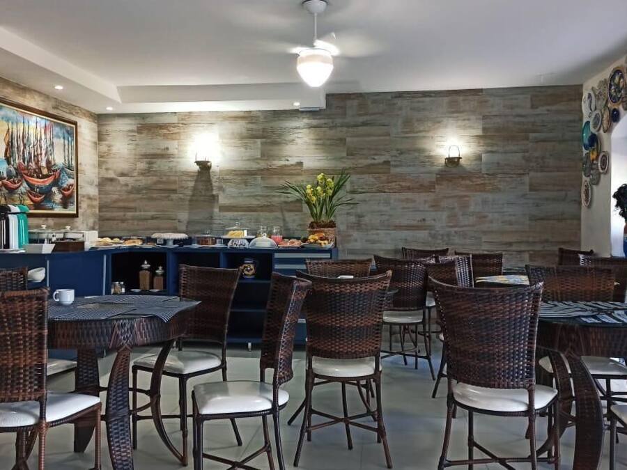 Un restaurante con sillas y mesas de mimbre, una zona de bufé y un mural en la pared.