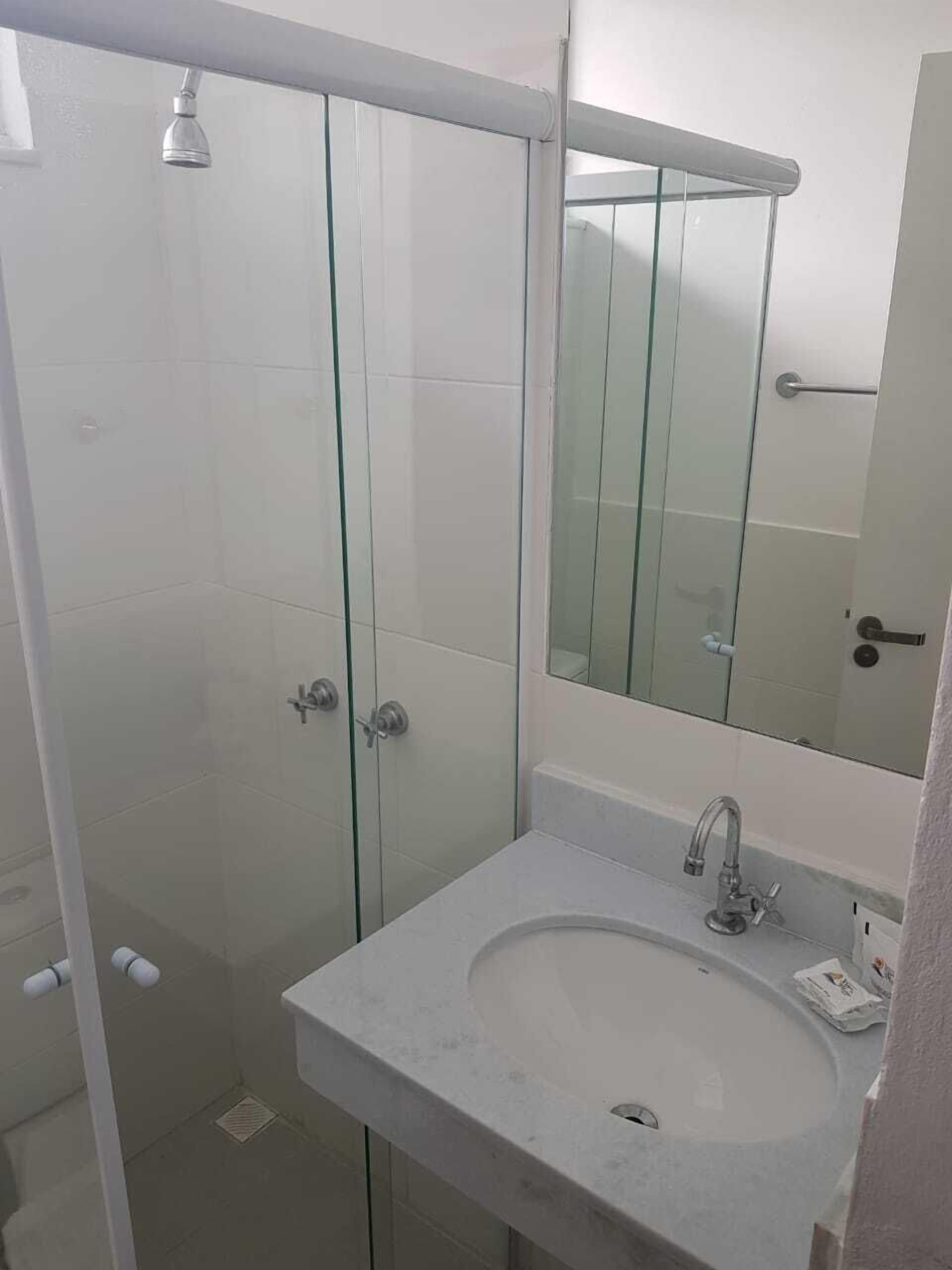 Un baño moderno con cabina de ducha de vidrio, un lavabo blanco y un espejo grande.