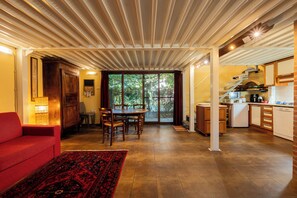 A spacious living area with a dining table and chairs, a red sofa, and a kitchen area with appliances. - Campagna e Mare a Pochi Minuti da Costa Rei (Castiadas)