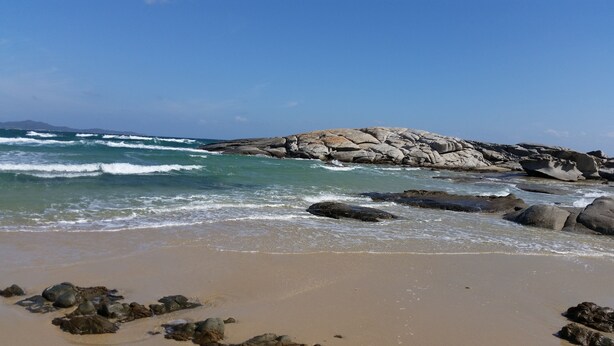 A beach with rocky formations and waves.
