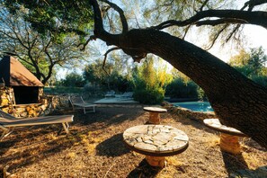 Área de pátio com cadeiras de lounge, uma mesa de pedra e uma piscina.