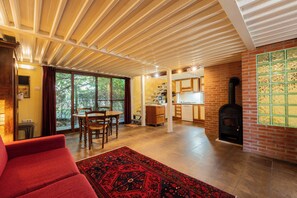A spacious living area with a dining table, a red sofa, and a fireplace. - Campagna e Mare a Pochi Minuti da Costa Rei (Castiadas)