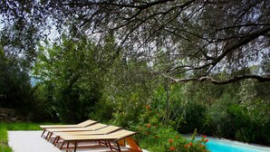 A poolside area with lounge chairs and a stone wall.