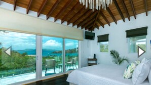 Un dormitorio con una cama grande, vistas al mar y un balcón con mobiliario exterior.