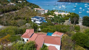 Una propiedad costera con una casa de techo rojo, piscina y vista al mar con barcos.