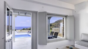 Una habitación moderna con un amplio ventanal con vistas a una piscina y al mar.