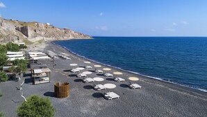 Una playa con tumbonas y sombrillas dispuestas en una orilla pedregosa, con vista al mar.