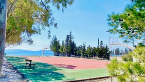 A basketball court with a bench, surrounded by trees and a clear view of the sea. - Villasonboard Dock Villa 3bed Sleeps8 Porto Hydra (Ermionida)