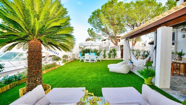 A well-maintained outdoor patio with a lush green lawn, white outdoor furniture, and a hammock. - Villasonboard Dock Villa 3bed Sleeps8 Porto Hydra (Ermionida)
