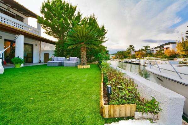 A well-maintained lawn with outdoor furniture, a boat dock, and a house with a balcony.