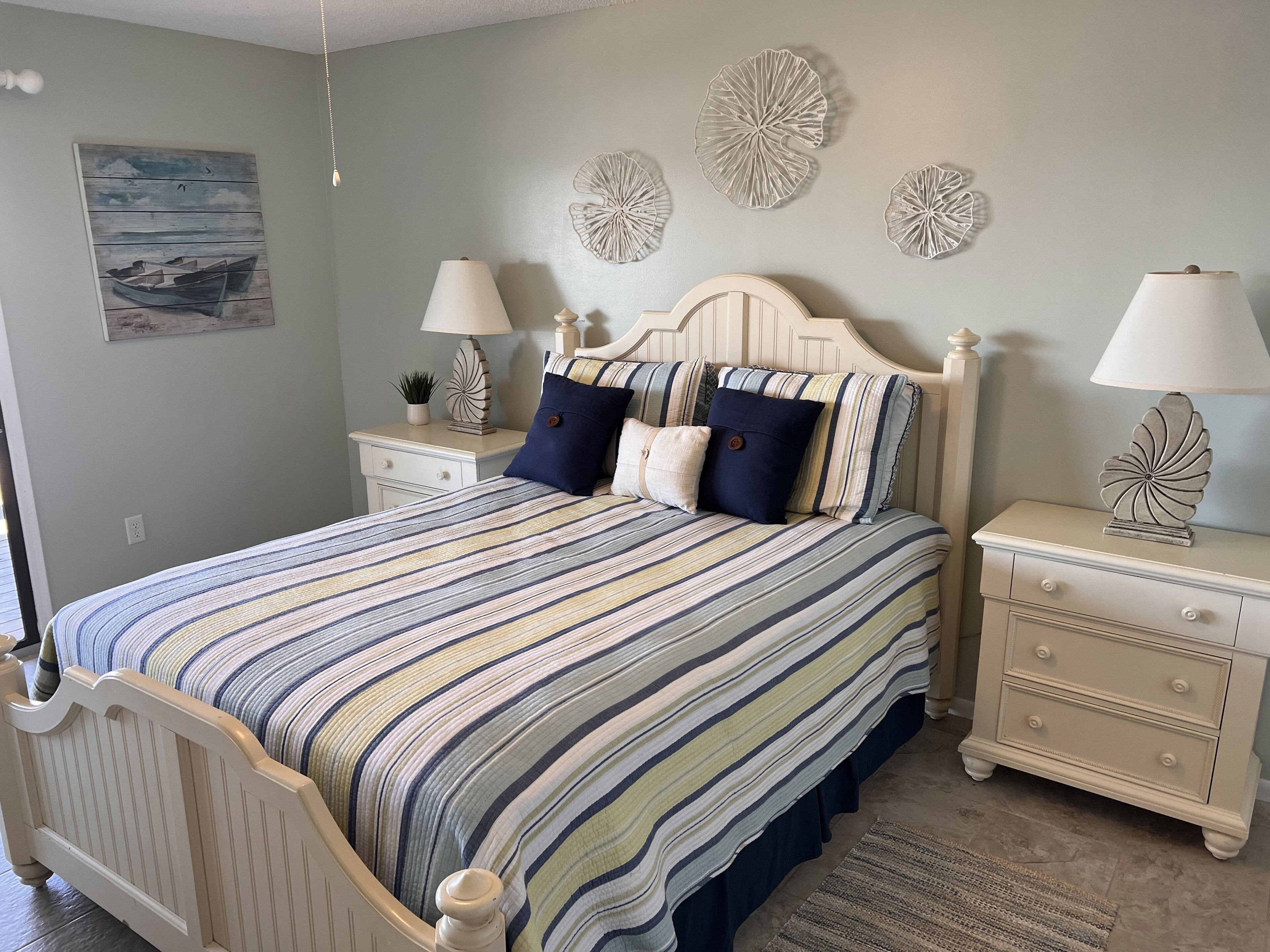 Un dormitorio con una cama, dos mesitas de noche, decoración en la pared y un cuadro.
