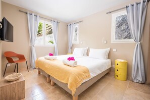 Een hotelkamer met een bed, een stoel, een klein tafeltje en een geel bijzettafeltje.
