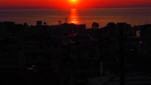 Un atardecer sobre una ciudad costera, con edificios recortados contra el cielo.