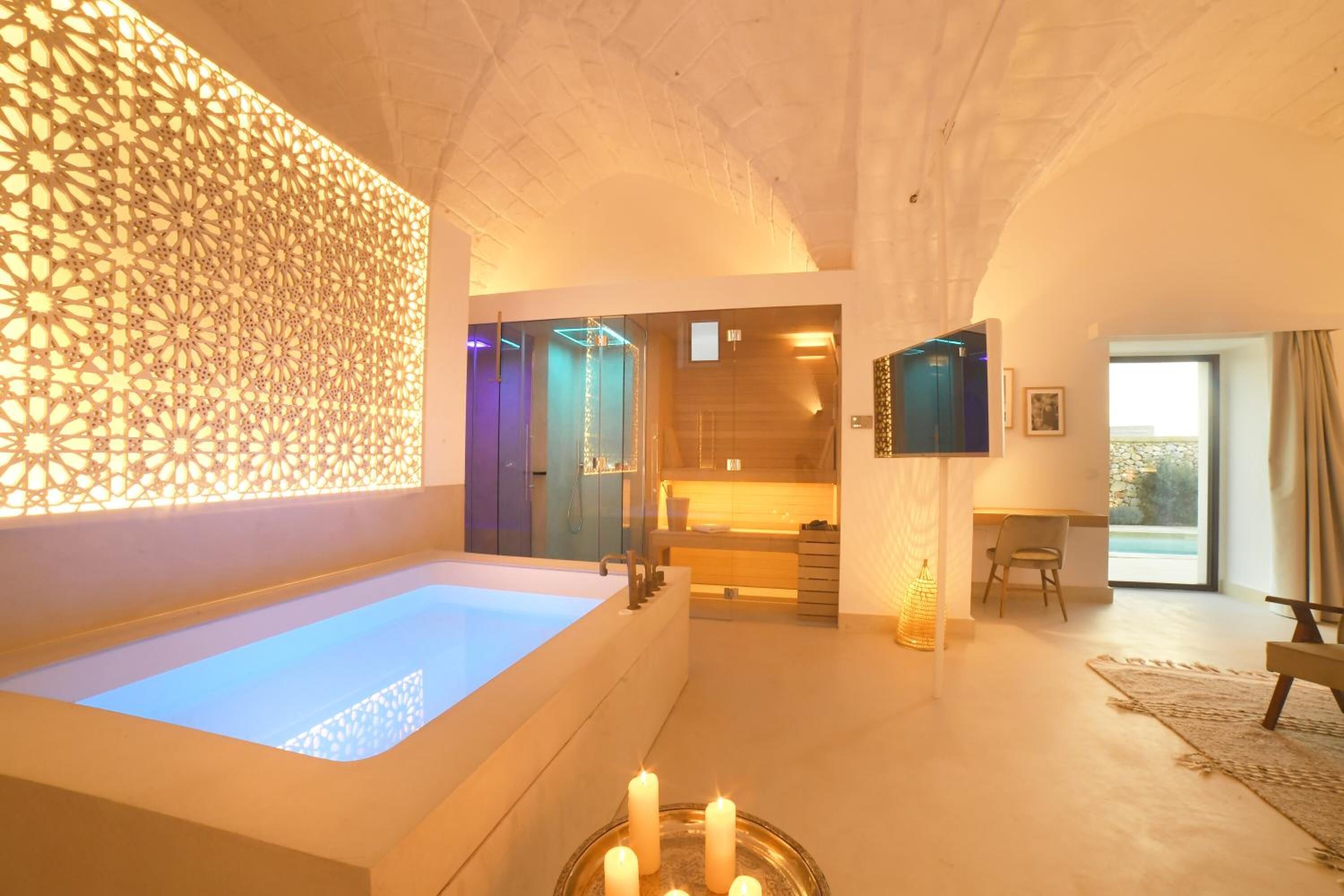 A modern bathroom with a large bathtub, a decorative wall, and a glass shower enclosure.