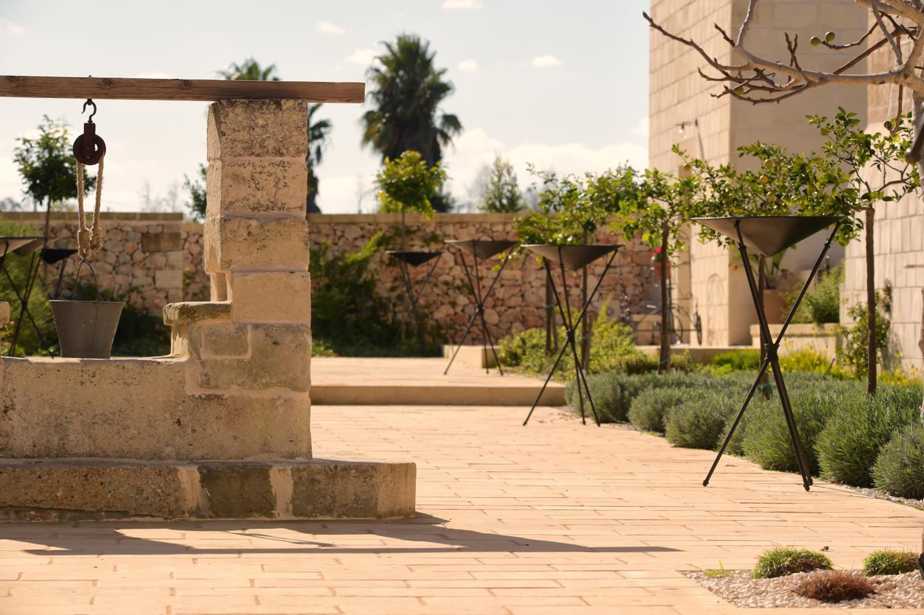 Une cour avec une fontaine en pierre, une pergola et un bâtiment en arrière-plan.