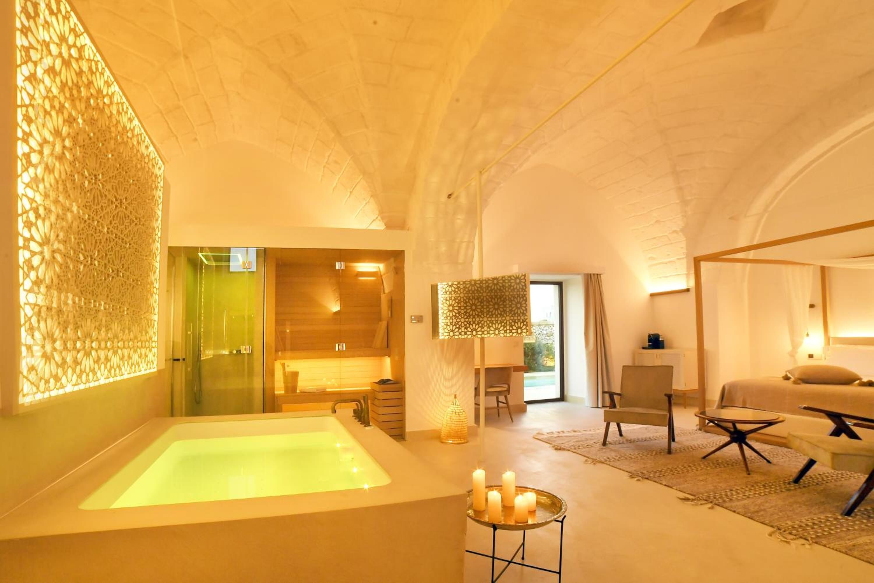 A modern spa room with a large bathtub, a glass-enclosed shower, and a seating area with a table and chairs.