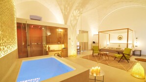 A spa area with a large bathtub, a massage table, and a seating area with chairs and a small table.