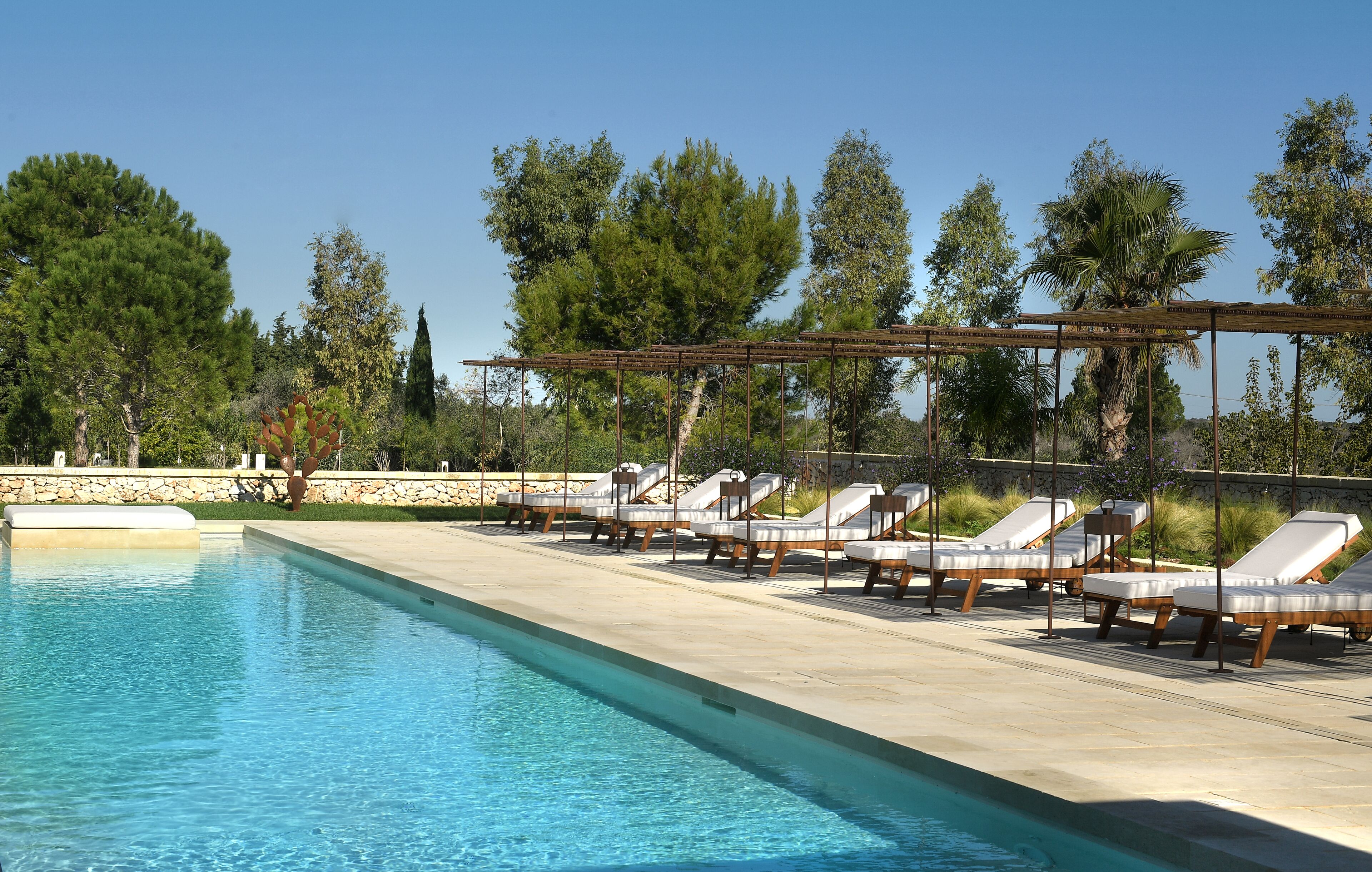 A swimming pool with lounge chairs and a pergola.