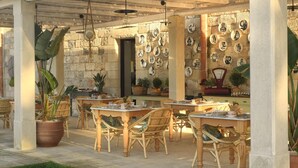 An outdoor patio with wicker furniture, stone walls, and potted plants.