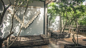 Un espace extérieur abrité, agrémenté de jardinières en bois et d’éléments décoratifs suspendus.