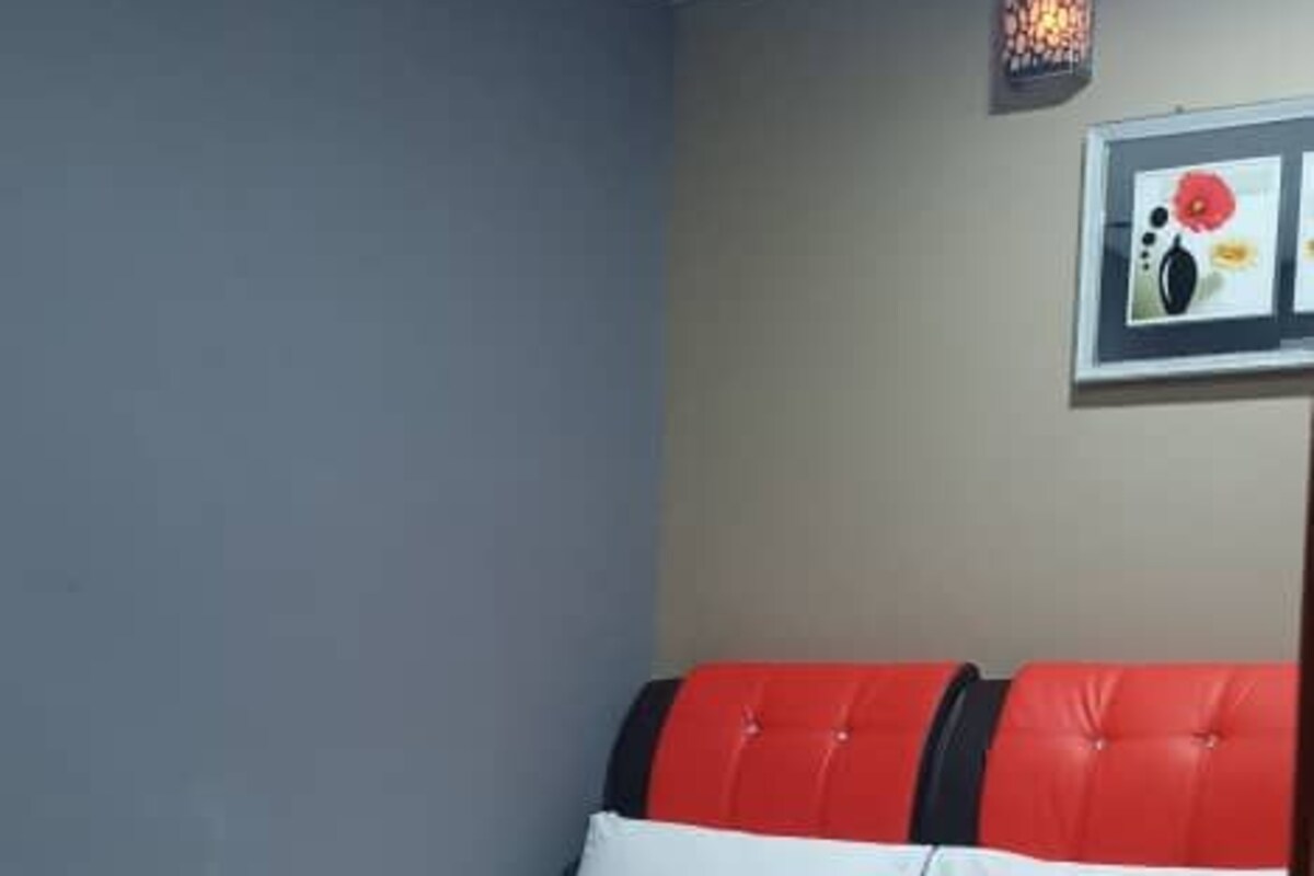 A hotel room with a bed, a wall-mounted light fixture, and a framed picture.