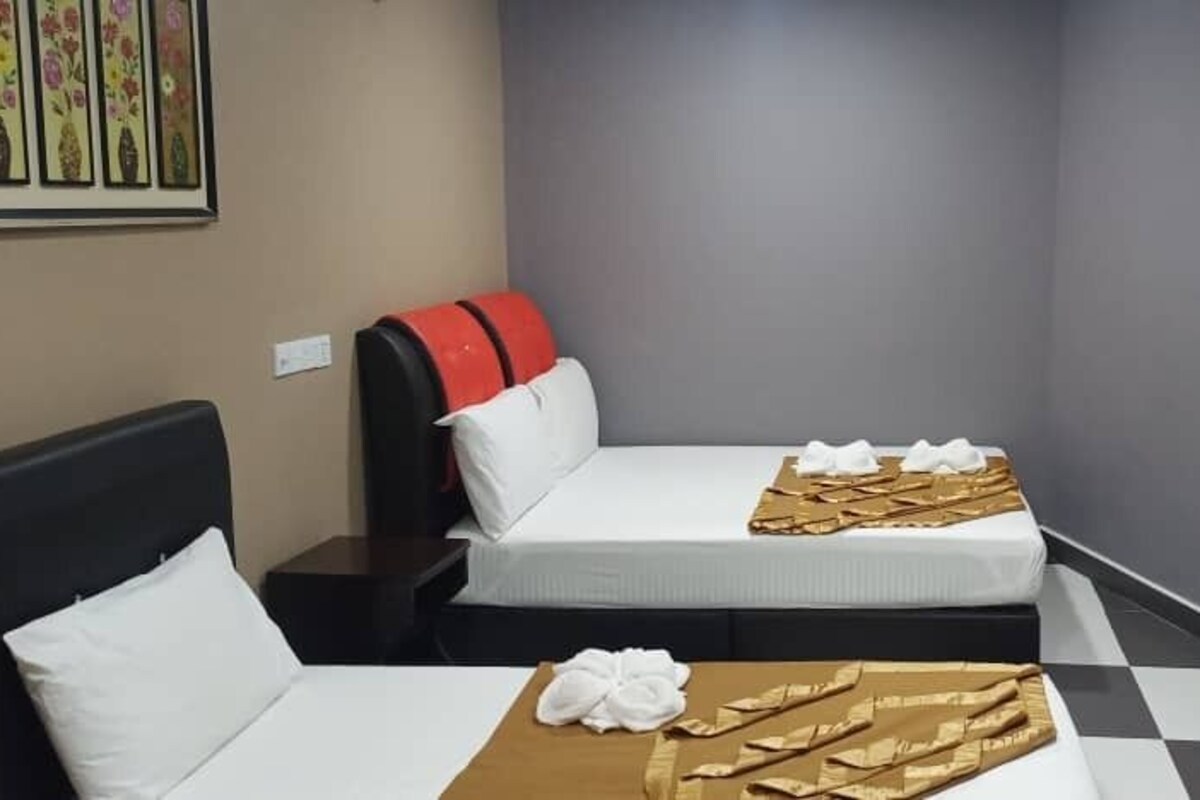 A hotel room with two beds, a checkered floor, and a small shelf with a decorative item.