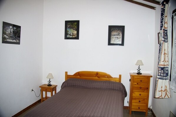 A bedroom with a wooden bed, two bedside tables, and three framed pictures on the wall. - A Ficandiana, 6 km from the sea, panoramic mountain views, garden, Wi-Fi, air conditioning (Sartène)