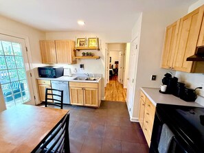 A compact kitchen with wooden cabinets, a microwave, and a coffee machine. - Chic Condo in Downtown Raleigh (Raleigh)