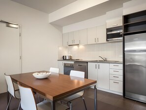 Una cocina moderna con armarios blancos, electrodomésticos de acero inoxidable y una mesa de comedor de madera.